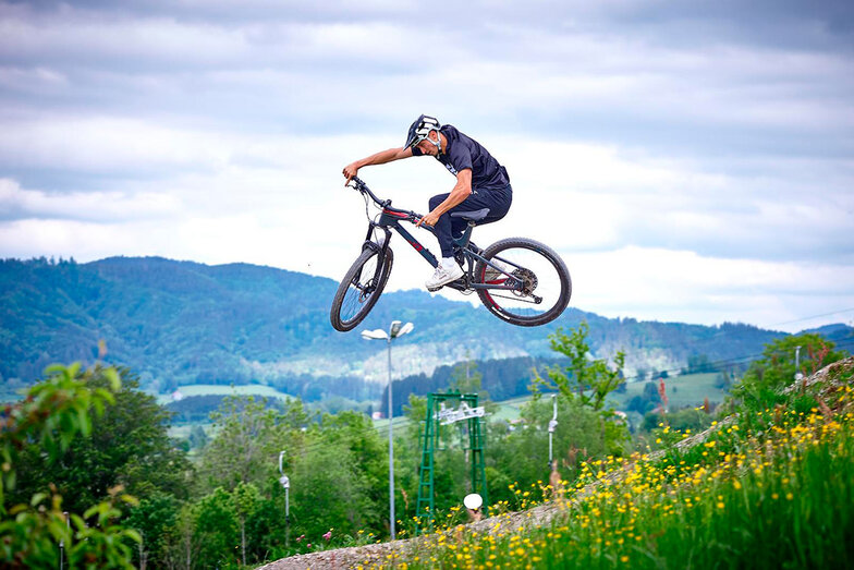 Sportlicher Fahrradfahrer der in einer herrlichen Landschaft mit seinem Sportrad Sprünge in die Luft macht