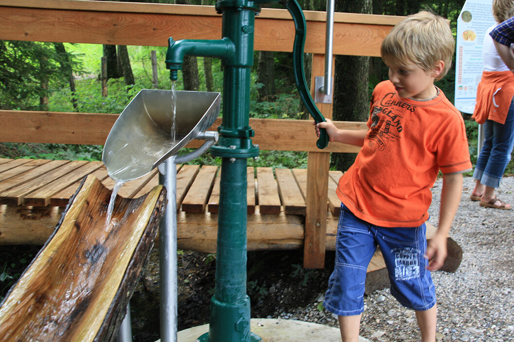 kleiner Junge der mit einer Wasserrutsche am Pfaffenwinkler Milchweg im Wald spielt